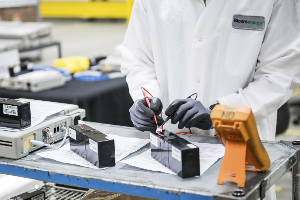 FILE - In this March 28, 2020, file photo, David Yee, an NPI mechanical engineer, tests voltage of new batteries at Bloom Energy in Sunnyvale, Calif. The COVID-19 outbreak has prompted companies large and small to rethink how they do business. Bloom Energy makes hydrogen fuel cells. But recently, they have been refurbishing old ventilators so hospitals can use them to keep coronavirus patients alive. (Beth LaBerge/KQED via AP, Pool, File)