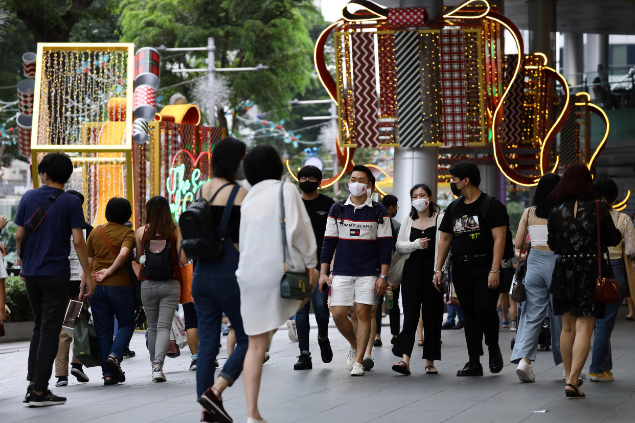 SINGAPORE - DECEMBER 24: People wearing protective mask walk past Christmas decorations along the Orchard Road shopping belt on December 24, 2020 in Singapore. As Singapore prepares to further ease COVID-19 restrictions from December 28, the government reported its first COVID-19 case carrying the potentially more contagious strain of the virus circulating in the United Kingdom yesterday. As of 24 December, the Ministry of Health confirmed 13 new imported COVID-19 cases in the wider community bringing the country's total to 58,495. (Photo by Suhaimi Abdullah/Getty Images)