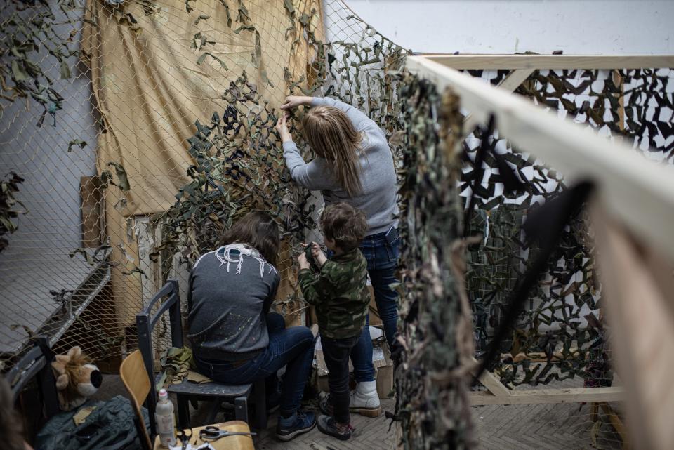 Two women and a child weave a camouflage net on March 16, 2022 in Lviv, Ukraine.