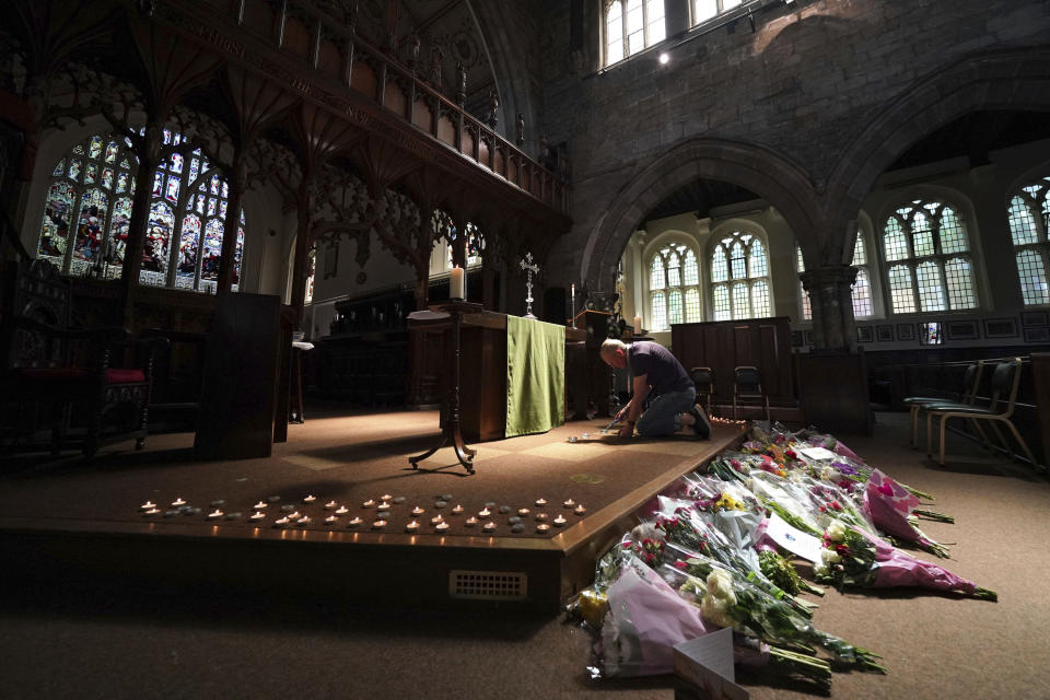 A man lights a candle in St Peter's church, after three people were killed and three hurt in connected attacks on Tuesday, in Nottingham, England, Wednesday June 14, 2023. Police in England are working to piece together details of a knife and van attack that killed two 19-year-old students and another man in the city of Nottingham. Nottingham University students Barnaby Webber and Grace Kumar were stabbed to death in a street before dawn on Tuesday. (Jacob King/PA via AP)