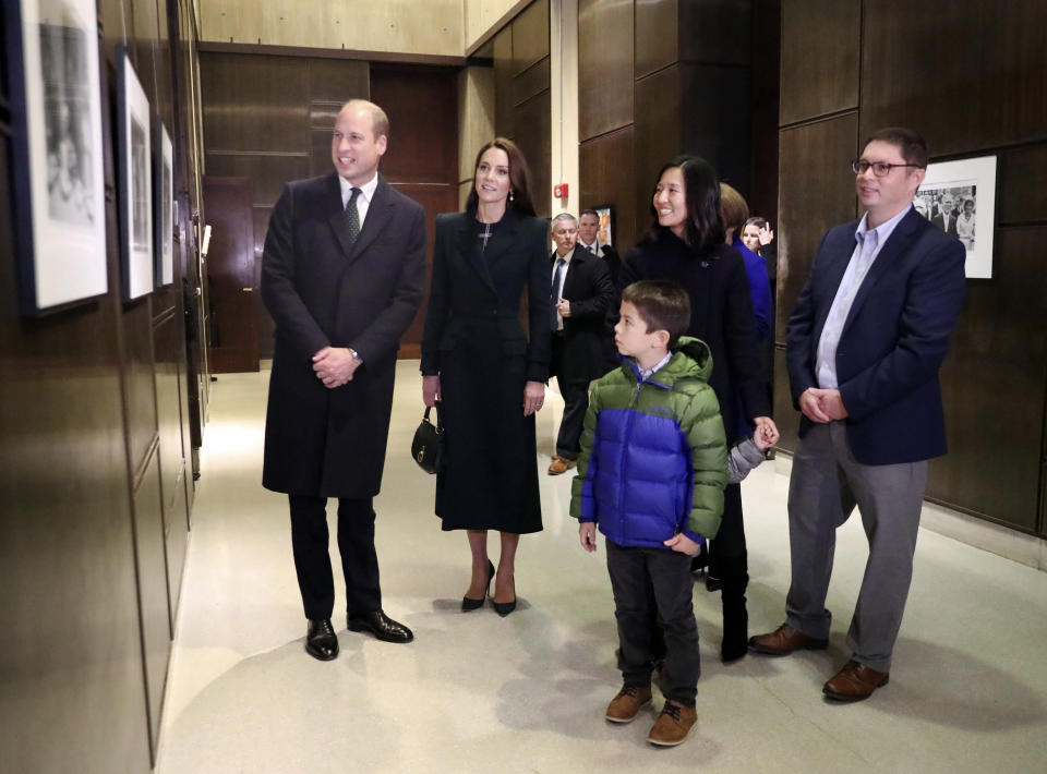 Boston Mayor Michelle Wu, right, husband Conor Perwarski, right, and sons Blaise, holds her hand, and Cass, front, show photographs of the Queen Elizabeth II's visit in 1976, during the visit of Britain's Prince William and Kate, Princess of Wales, to Boston City Hall on Wednesday, Nov. 30, 2022, in Boston. The Prince and Princess of Wales are making their first overseas trip since the death of Queen Elizabeth II in September. (Nancy Lane/The Boston Herald via AP, Pool)