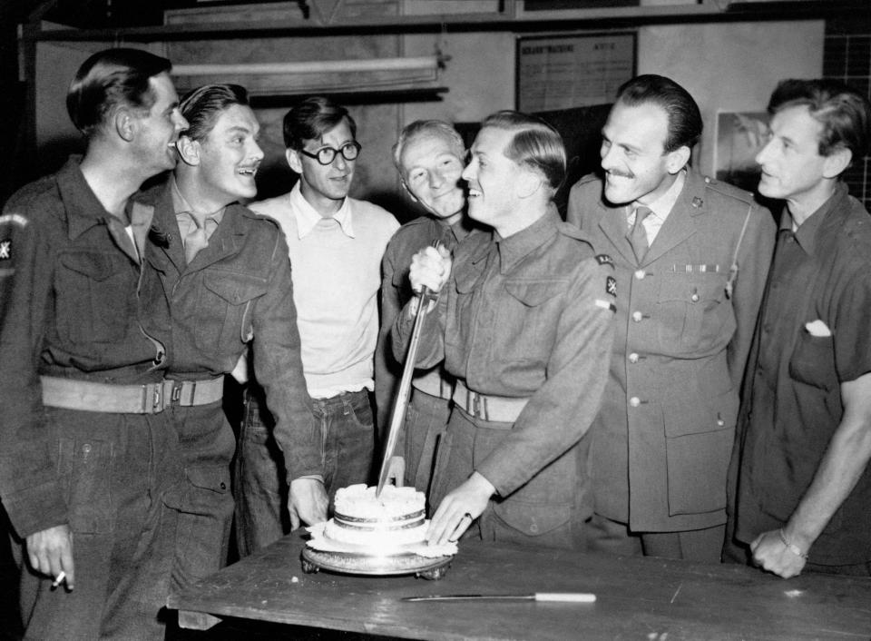 Richard Attenborough, who heads the cast of the Boulting Brothers' new film "Private's Progress", a satire on Army life, now being made at Shepperton Studio's, cuts his birthday cake with a bayonet during a tea break today. L to R: Ian Carmichael, Thorley Walters, John Boulting (director), William Hartnell, Richard Attenborough, Terry Thomas and Roy Boulting (producer)