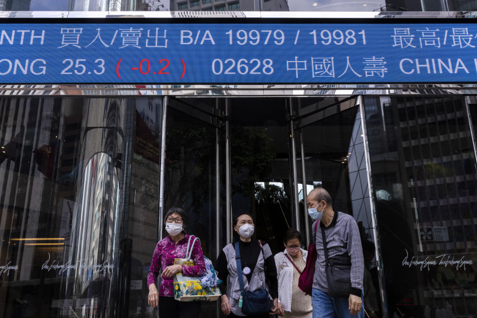 Pedestrians pass by the Hong Kong Stock Exchange electronic screen in Hong Kong Friday, March 24, 2023. (AP Photo/Louise Delmotte)