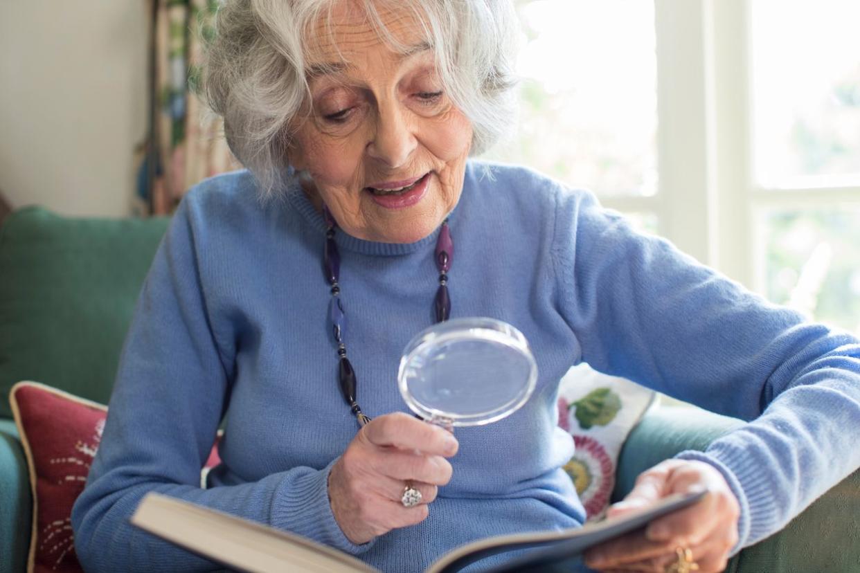 Senior uses a magnifying glass to read