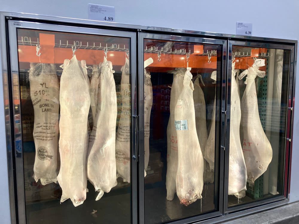 Rows of whole pigs are shown hanging in refrigerated sections of a Costco Business Center.