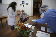 Olivia Bibe, 87, watches as municipal worker Mario Matos, right, seals an envelope with her presidential election ballot at the elderly care home where she resides in Montijo, south of Lisbon, Tuesday, Jan. 19, 2021. For 48 hours from Tuesday, local council crews are collecting the votes from people in home quarantine and from residents of elderly care homes ahead of Sunday's presidential election. (AP Photo/Armando Franca)