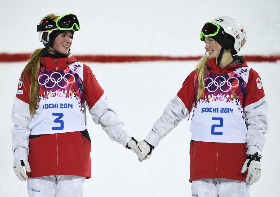 Second-placed Chloe Dufour-Lapointe of Canada and her sister, first-placed Justine Dufour-Lapointe, hold hands during the flower ceremony for the women's freestyle skiing moguls event at the Sochi 2014 Winter Olympics in Rosa Khutor
