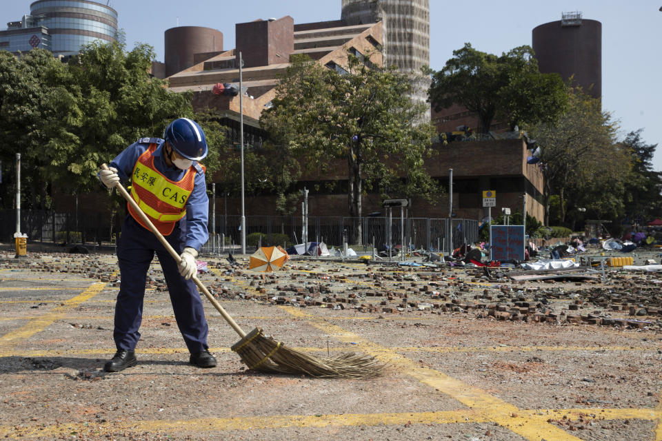 A worker sweeps the road outside the Polytechnic University in Hong Kong on Wednesday, Nov. 20, 2019. A small group of protesters refused to leave Hong Kong Polytechnic University, the remnants of hundreds who took over the campus for several days. They won't leave because they would face arrest. Police have set up a cordon around the area to prevent anyone from escaping. (AP Photo/Ng Han Guan)