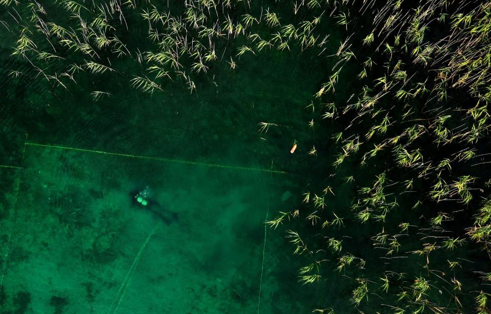 This photograph taken on July 27, 2023, shows a diver searching for archaeological material in Lake Ohrid, southeastern Albania. A mixed team of Albanian and Swiss archaelogists from the Univesity of Bern have confirmed that the the Palafitte settlement of Lin dates back to 5800 - 6,000 years BC, making it the oldest lakeside village in Europe discovered to date. The village is believed to have consisted of houses built on stilts above the lake's surface or in areas regularly flooded by rising waters.