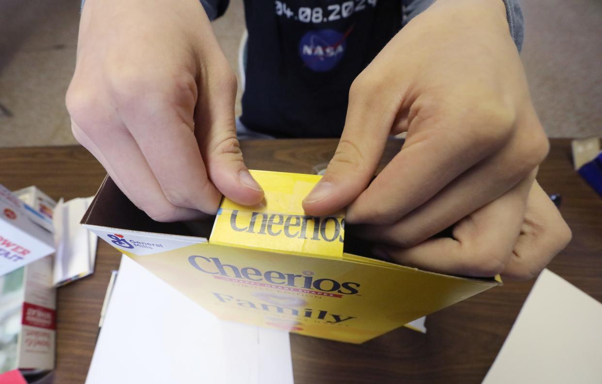 George Melis, a sophomore at Clarkstown South, shows the items needed to build a cereal box eclipse viewer at Cornell Cooperative Extension in Stony Point April 2, 2024. Step 4 - Fold the two remaining flaps over each other and tape them together.