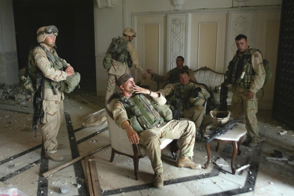 FILE - U.S. Army Stf. Sgt. Chad Touchett, center, relaxes with comrades from A Company, 3rd Battalion, 7th Infantry Regiment, following a search in one of Saddam Hussein's palaces damaged after a bombing, in Baghdad, in this April 7, 2003. (AP Photo/John Moore, File)