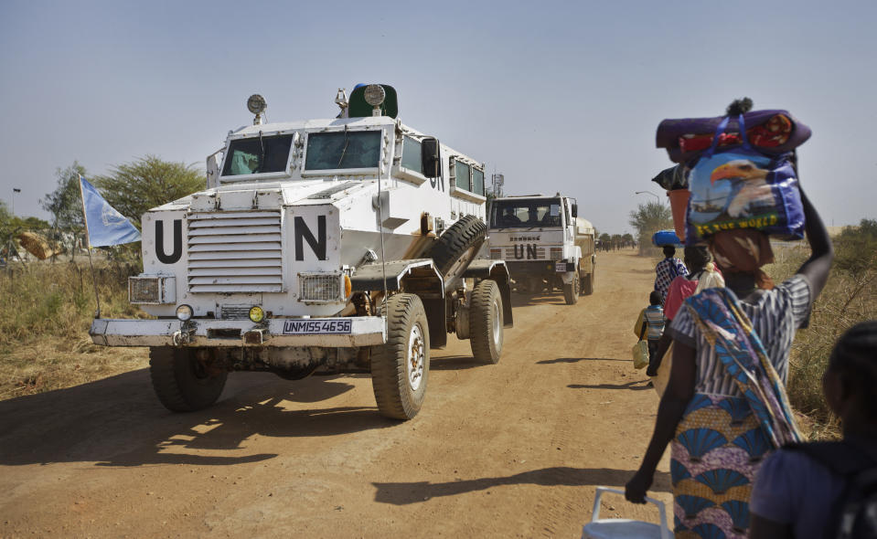 FILE - In this Monday, Dec. 30, 2013 file photo, a United Nations armored vehicle passes displaced people walking towards the U.N. Protection of Civilians camp in Malakal, South Sudan. The United Nations peacekeeping mission in South Sudan said on Friday, Sept. 4, 2020 that it has begun withdrawing its troops and police from the protection of civilians camps that continue to shelter more than 180,000 people two years after the end of the country's civil war. (AP Photo/Ben Curtis, File)