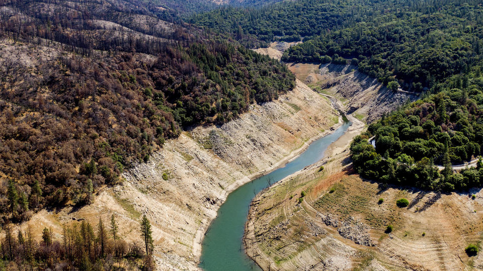 Dry banks rise above water in Lake Oroville on Sunday, May 23, 2021, in Oroville, Calif. At left are trees scorched in the 2020 North Complex Fire. At the time of this photo, the reservoir was at 39 percent of capacity and 46 percent of its historical average. California officials say the drought gripping the U.S. West is so severe it could cause one of the state's most important reservoirs to reach historic lows by late August, closing most boat ramps and shutting down a hydroelectric power plant during the peak demand of the hottest part of the summer. (AP Photo/Noah Berger)