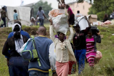 Foreigners from Zimbabwe carry their bags before boarding a bus home, from a camp for those affected by anti-immigrant violence in Chatsworth, north of Durban April 19, 2015. REUTERS/Rogan Ward