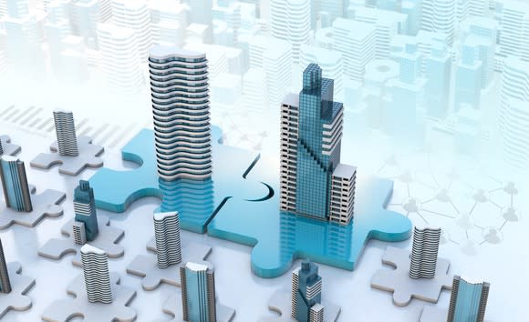 Two buildings on puzzle pieces, symbolizing a merger.