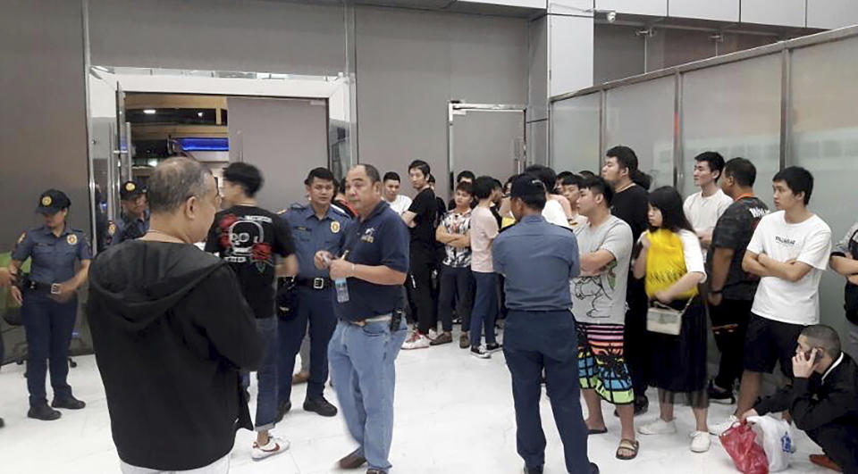 In this Oct. 9, 2019, photo provided by Philippine Bureau of Immigration, foreign nationals, mostly Chinese are herded in a room during a raid of their company premises in Manila, Philippines. Philippine police and immigration authorities said they have arrested more than 500 illegally working foreigners, mostly Chinese involved in telecommunications and investment scams, in one of the biggest such mass arrests this year. (Philippine Bureau of Immigration via AP)