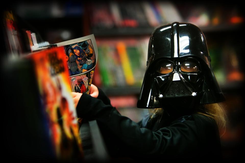 Kate Sullivan, 5, of North East, MD is caught reading some comics in her Darth Vader outfit as she hangs out on Magic Friday night at Comicmania in Wilmington.