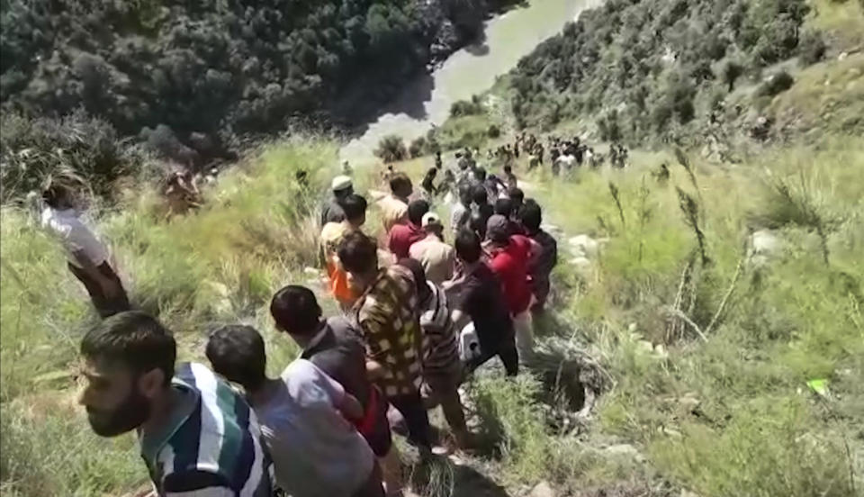 In this grab made from video provided by KK Productions, rescuers try to reach a bus that fell into a gorge in Kishtwar, about 217 kilometers (135 miles) southeast of Srinagar, Indian-controlled portion of Kashmir, Friday, Sept. 14, 2018. The bus fell off a road into a deep gorge killing more than a dozen people. (KK Productions via AP)