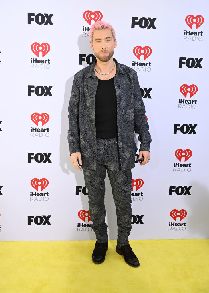 Lance Bass wearing a textured suit with casual t-shirt, posing at iHeartRadio event