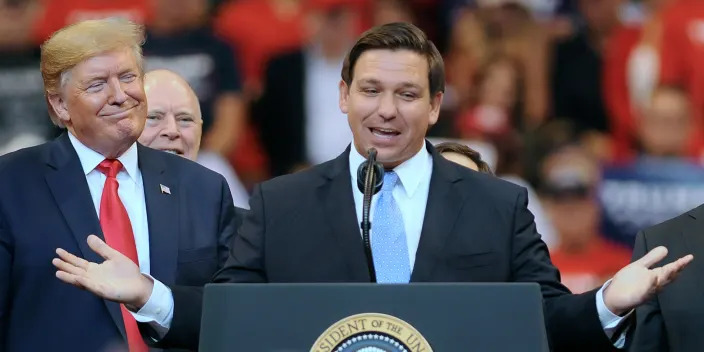 DeSantis speaking at podium next to Trump