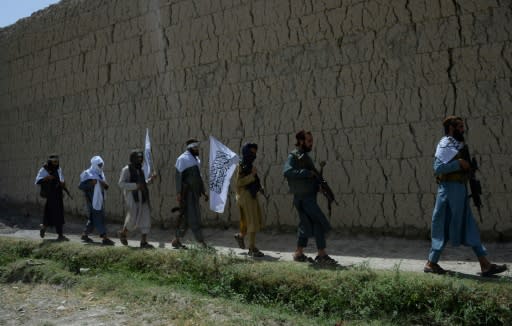 Taliban militants walk to celebrate an earlier ceasefire on the second day of Eid in the outskirts of Jalalabad