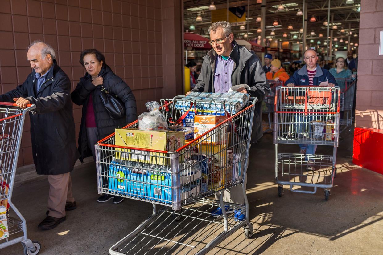 people leaving Costco with filled carts