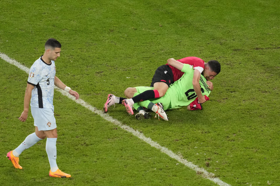 Georgia's goalkeeper Giorgi Mamardashvili is hugged by a team mate as he celebrates at the end of a Group F match between Georgia and Portugal at the Euro 2024 soccer tournament in Gelsenkirchen, Germany, Wednesday, June 26, 2024. (AP Photo/Andreea Alexandru)