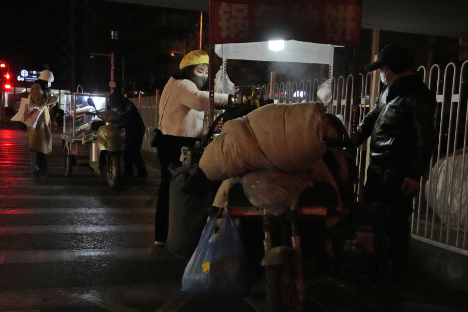 A resident buys fried noodles from a street vendor in Beijing, Wednesday, Dec. 28, 2022. China is on a bumpy road back to normal life as schools, shopping malls and restaurants fill up again following the abrupt end of some of the world's most severe restrictions even as hospitals are swamped with feverish, wheezing COVID-19 patients. (AP Photo/Ng Han Guan)