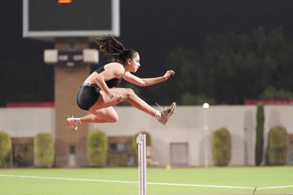Olympic athlete jumping over a hurdle on a race track