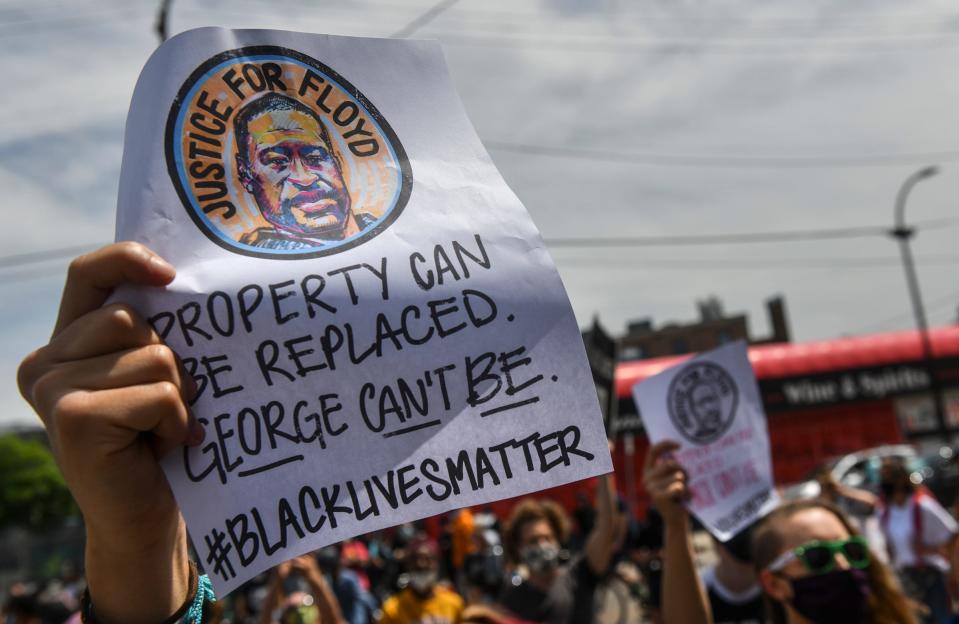 People hold signs near the Minneapolis Police Department's Third Precinct headquarters during protests following the death of George Floyd.