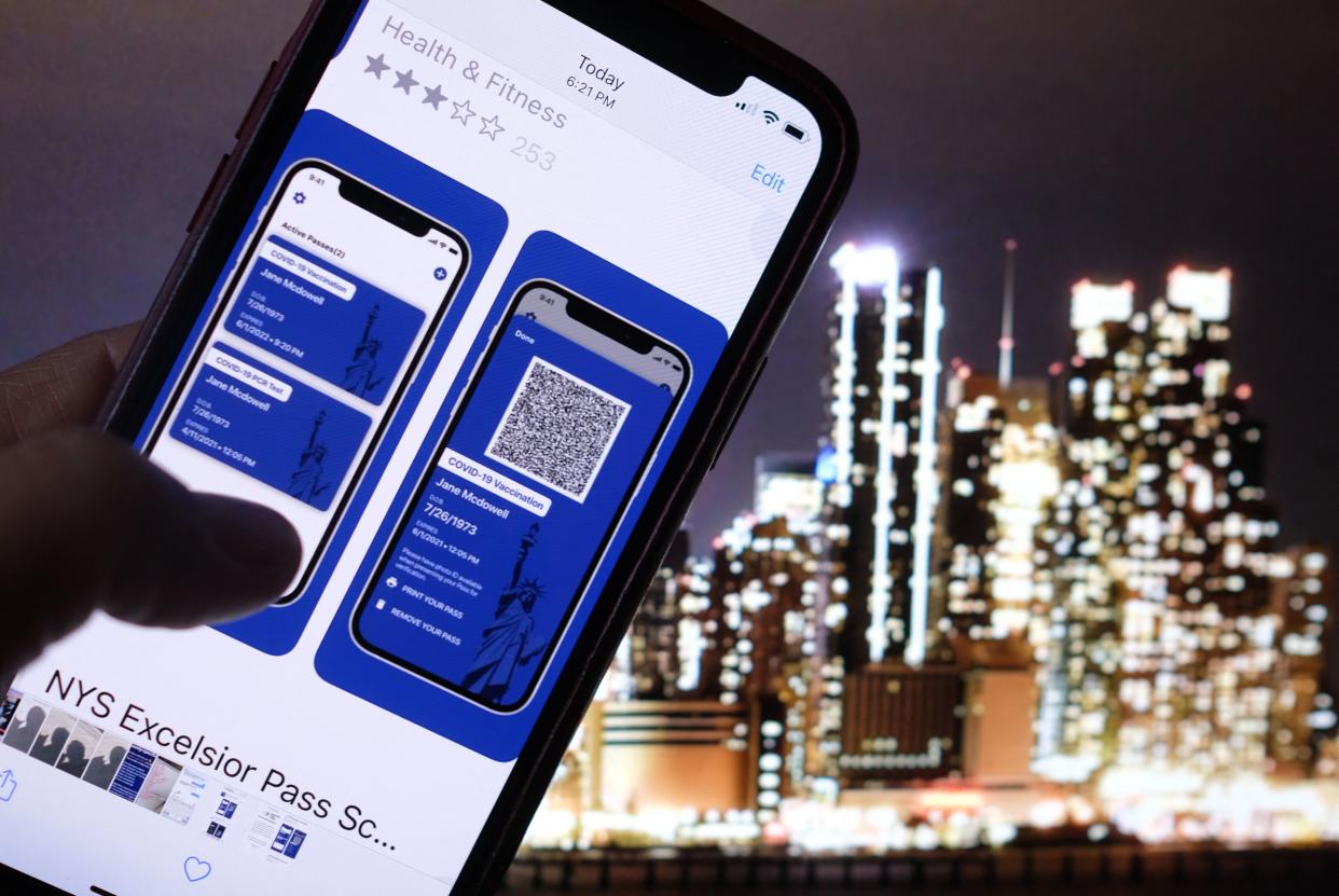 TOPSHOT - This illustration photo taken in Los Angeles on April 6, 2021 shows a person looking at the app for the New York State Excelsior Pass, which provides secure, digital proof of a Covid-19 vaccination, in front of a screen showing the New York skyline. - As the United States' vaccination campaign accelerates, so-called vaccine passports are gaining traction despite political divisions and a fragmented health care system that complicates the centralization of data. (Photo by Chris DELMAS / AFP) (Photo by CHRIS DELMAS/AFP via Getty Images)
