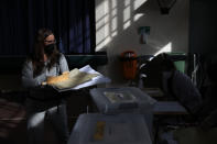 A voter carries her ballot during the Constitutional Convention election to select assembly members that will draft a new constitution, in Santiago, Chile, Saturday, May 15, 2021. The face of a new Chile begins taking shape this weekend as the South American country elects 155 people to draft a constitution to replace one that has governed it since being imposed during a military dictatorship. (AP Photo/Esteban Felix)