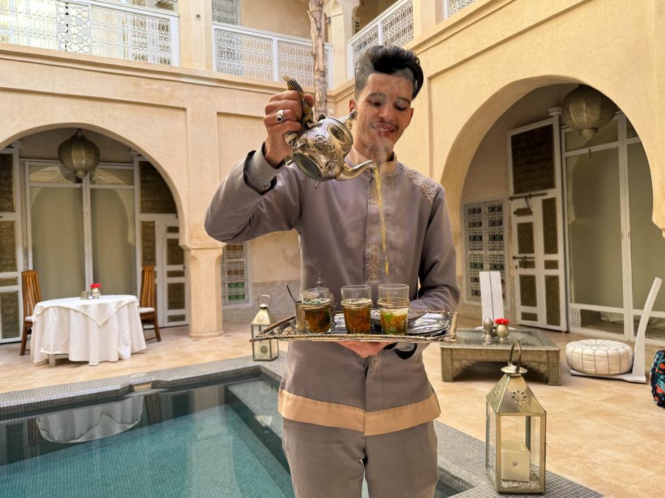 staff pouring tea by the pool at anayela riad in morocco
