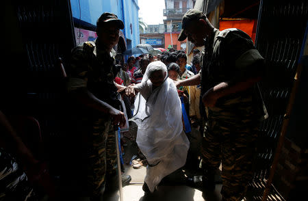 Security personnel help a woman enter a polling station to cast her vote during the fifth phase of general election in Howrah, on the outskirts of Kolkata, India May 6, 2019. REUTERS/Rupak De Chowdhuri