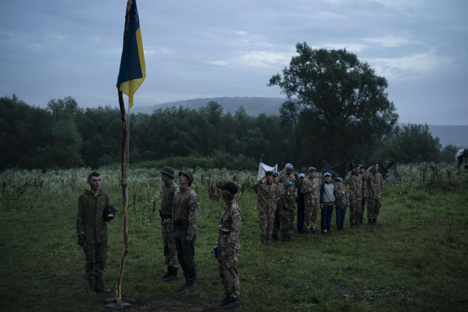 In this July 28, 2018 photo, young participants and instructors of the "Temper of will" summer camp, organized by the nationalist Svoboda party, stand in formation as they sing the national anthem in a village near Ternopil, Ukraine. Earlier this year, the Ministry of Youth and Sports earmarked 4 million hryvnias (about $150,000) to fund some of the youth camps among the dozens built by the nationalists. (AP Photo/Felipe Dana)