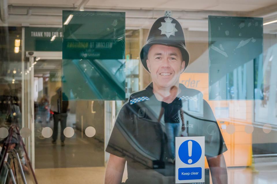 Crawley, UK - July 12, 2019 - a real size photograph of a policeman on a glass wall of Morisons supermarket, as a warning for possible thiefs