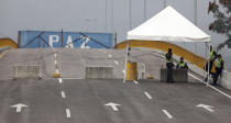 Colombian police stand on the Colombian side of the Tienditas International Bridge, which is blocked with a cargo trailer, a fuel tanker and fencing, placed by Venezuelan authorities to block humanitarian aid from entering, on the outskirts of Cucuta, Colombia, on the border with Venezuela, Monday, Feb. 18, 2019. Juan Guaido, who declared himself interim president of Venezuela on Jan. 23 with the backing of the U.S. and most South American and European nations, announced that humanitarian aid will enter Venezuela on Saturday, Feb. 23, the day after Richard Branson's concert at the same site. (AP Photo/Fernando Vergara)