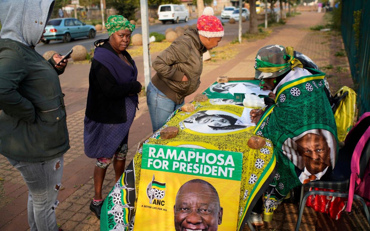Voters register with African National Congress volunteers before casting their ballot - AP