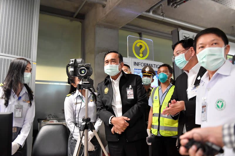 Thailand's Prime Minister Prayuth Chan-ocha wearing a protective mask looks through a thermographic imaging device during a visit at the arrival hall at the Bangkok's Suvarnabhumi International airport