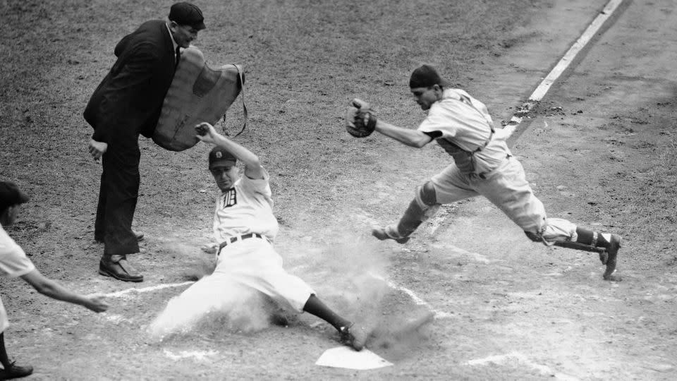 Hank Greenberg crosses the plate with the third run as Aaron Robinson makes a stab for him in July 1946. - AP