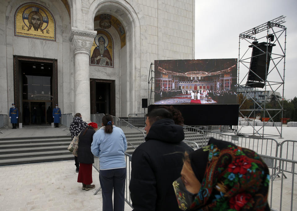 Believers stand in front of St. Sava Temple during the funeral procession of Patriarch Irinej in Belgrade, Serbia, Sunday, Nov. 22, 2020. The 90-year-old Irinej died early on Friday, nearly three weeks after he led the prayers at a funeral of another senior church cleric in neighboring Montenegro, who also died after testing positive for the virus. (AP Photo/Darko Vojinovic)