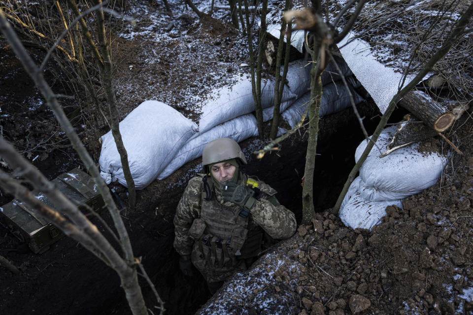 FILE - A Ukrainian serviceman smokes a cigarette at his position on the frontline near Bakhmut, Donetsk region, Ukraine, Wednesday, Jan. 11, 2023. War has been a catastrophe for Ukraine and a crisis for the globe. One year on, thousands of civilians are dead, and countless buildings have been destroyed. Hundreds of thousands of troops have been killed or wounded on each side. Beyond Ukraine’s borders, the invasion shattered European security, redrew nations’ relations with one another and frayed a tightly woven global economy. (AP Photo/Evgeniy Maloletka, File)