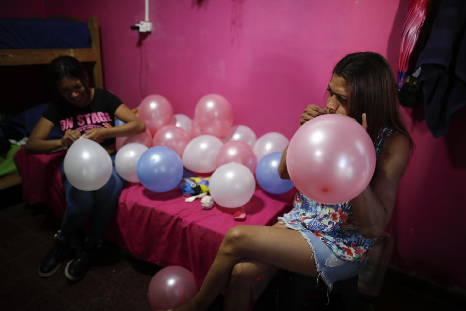 Transgender woman Lourdes Figueroa inflates balloons at Hotel Gondolin, where she lives, to celebrate Pride Day in Buenos Aires, Argentina, Saturday, Nov. 7, 2020. In September, President Alberto Fernández signed a decree establishing a 1% employment quota for transgender people in the public sector. (AP Photo/Natacha Pisarenko)