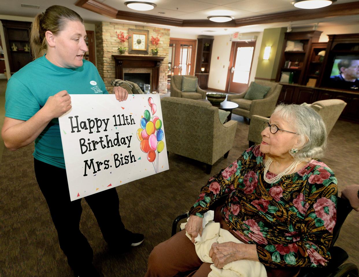 Vicky Kacevicius, left, human resource manager at The Villas Senior Care Community in Sherman, shows Wenonah Bish a sign that she had made up for Bish's 111th birthday on Monday.