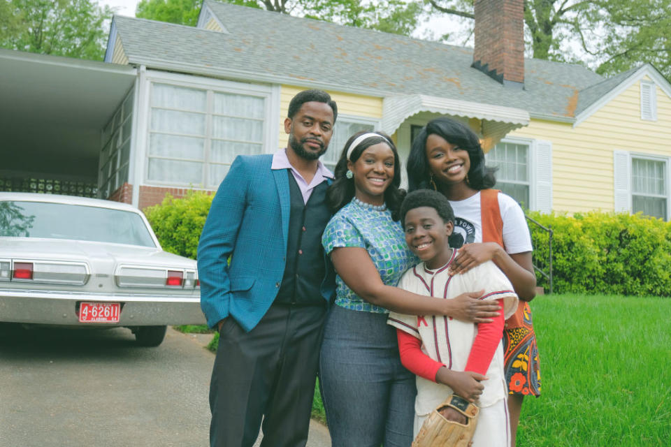 A family of four smiling and posing together outside their home