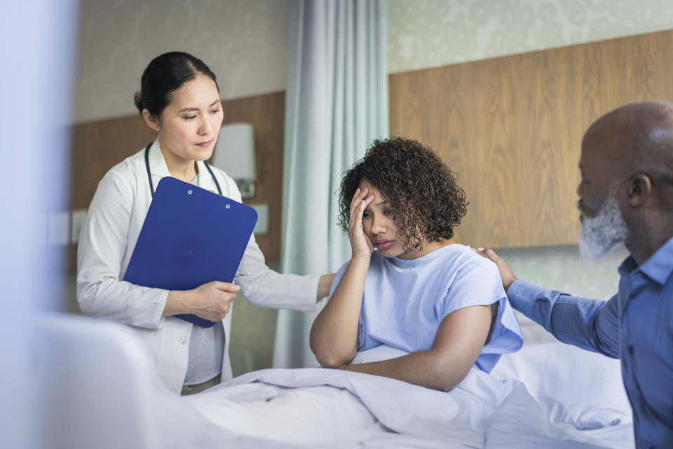 A doctor holding a clipboard and man console depressed patient.