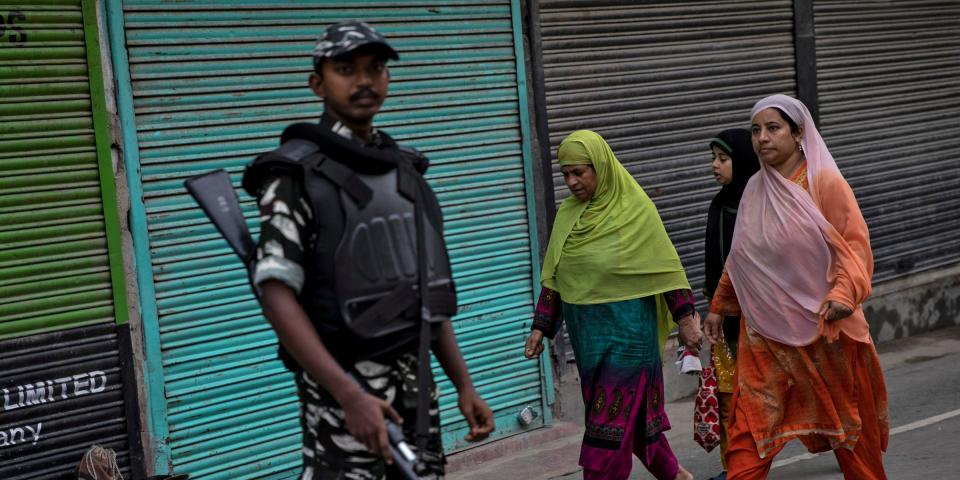 FILE PHOTO: Kashmiri women walk past an Indian security personnel during restrictions after the scrapping of the special constitutional status for Kashmir by the government, in Srinagar, August 11, 2019. REUTERS/Danish Siddiqui/File Photo