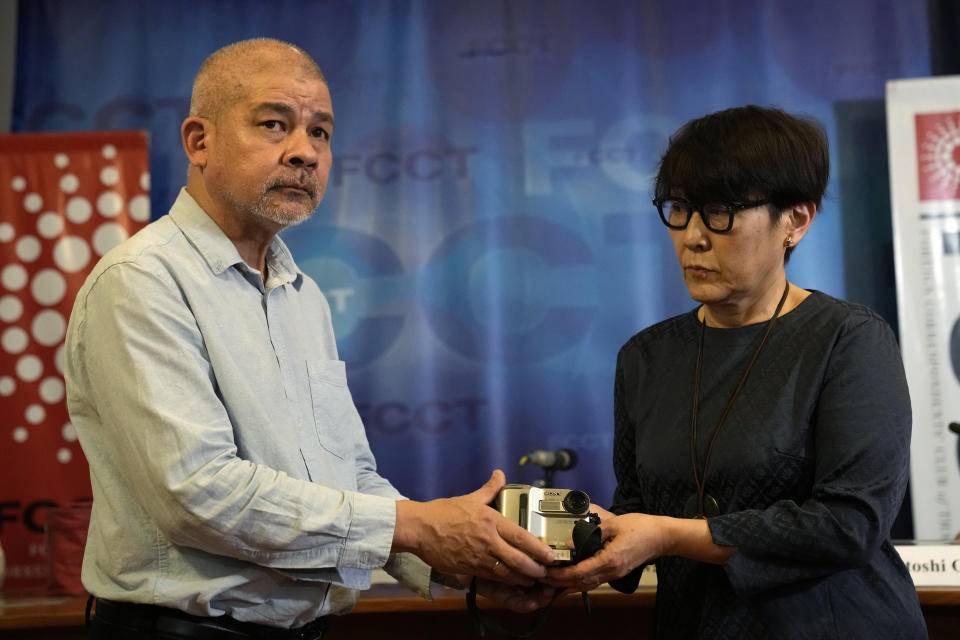 Aye Chan Naing, left, of Democratic Voice of Burma, hands over the video camera of slain Japanese journalist Kenji Nagai to his sister Noriko Ogawa, at the Foreign Correspondents Club in Bangkok, Thailand Wednesday, April 26, 2023. Nagai's video camera, which he had been carrying when he was shot dead covering a during a street protest in Myanmar September 2007, was missing until it was recently recovered by the Democratic Voice of Burma news service, which handed it over to his sister at the club. (AP Photo/Sakchai Lalit)