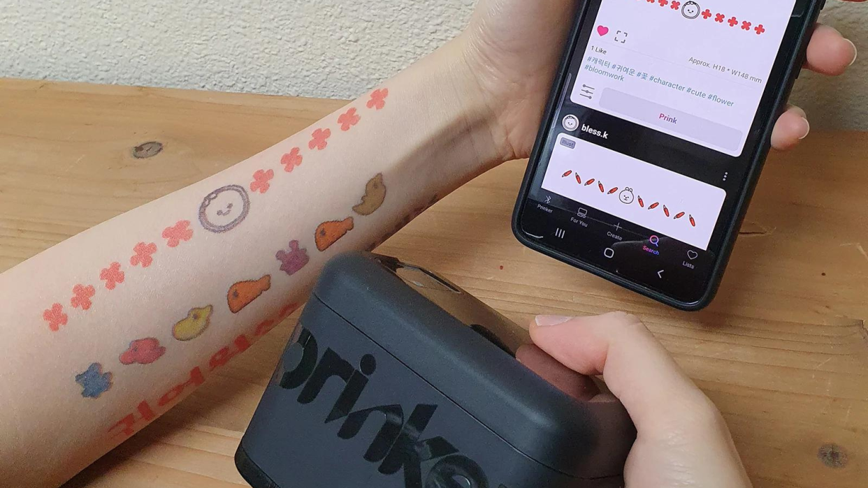 person using prinker m mobile to temporarily tattoo arm