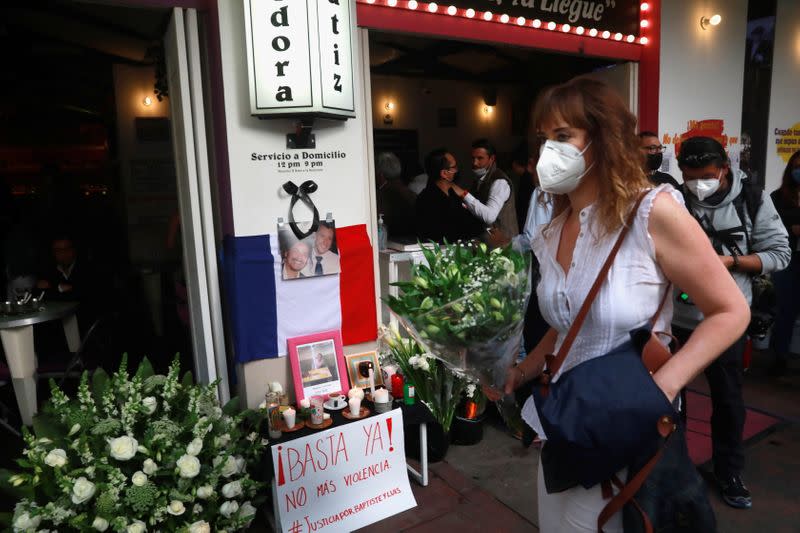 A member of the French community living in Mexico holds flowers past an altar outside a restaurant owned by French businessman Baptiste Jacques Daniel Lormand after he was found murdered, in Mexico City